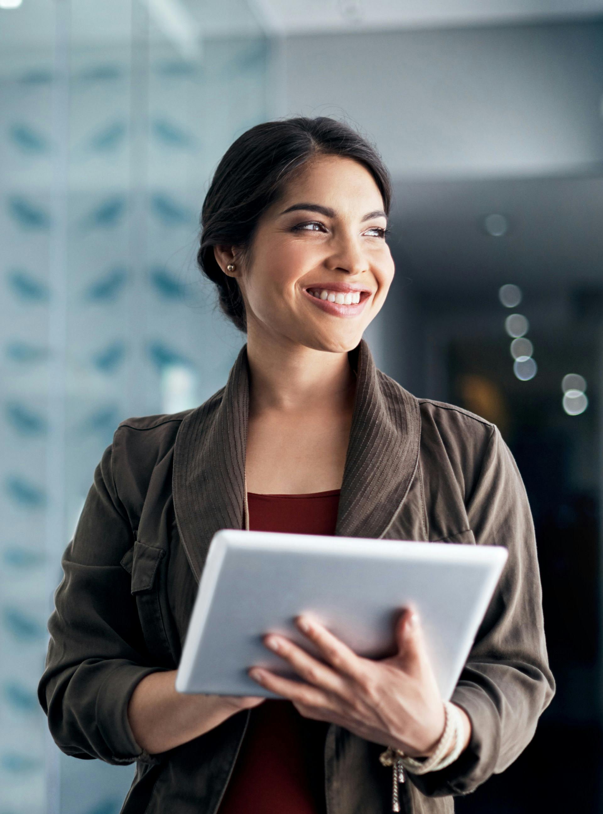 Woman standing and smiling holding a tablet